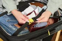 A person secures a strap lock on the Delsey Paris Shadow 5.0 Carry-on with Laptop Compartment