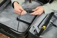 A person adjusts the lock on the Delsey Paris Shadow 5.0 Carry-on with Laptop Compartment