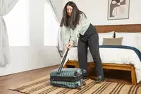 A person hits the Delsey Paris Shadow 5.0 Carry-on with Laptop Compartment with a baseball bat