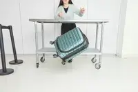 A person throws the Delsey Paris Shadow 5.0 Carry-on with Laptop Compartment off of a wheeled cart