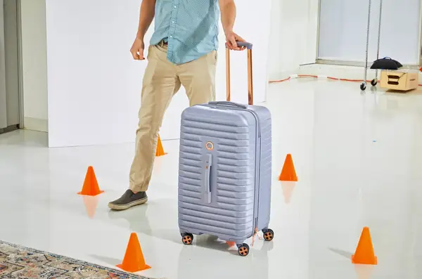 A person rolling the Delsey Paris Cruise 3.0 26 Inch Trunk through cones