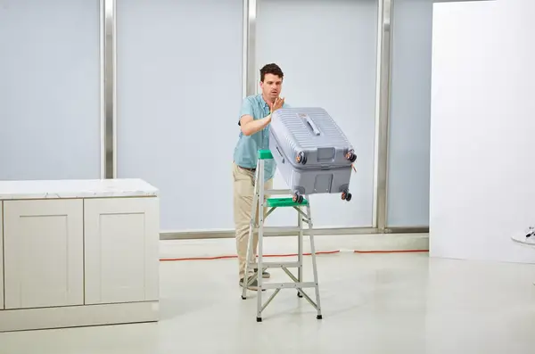 A person pushing the Delsey Paris Cruise 3.0 26 Inch Trunk off of a ladder