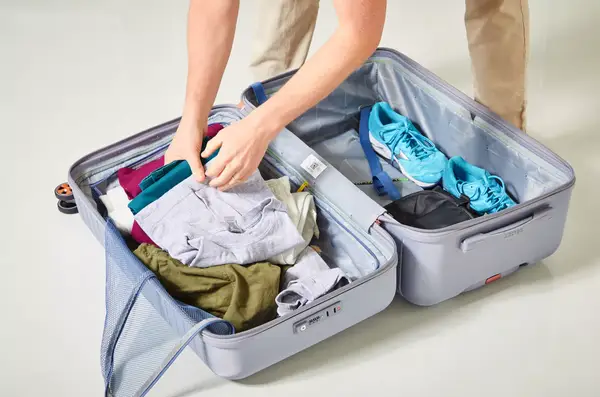 two hands placing items into the Delsey Paris Cruise 3.0 26 Inch Trunk