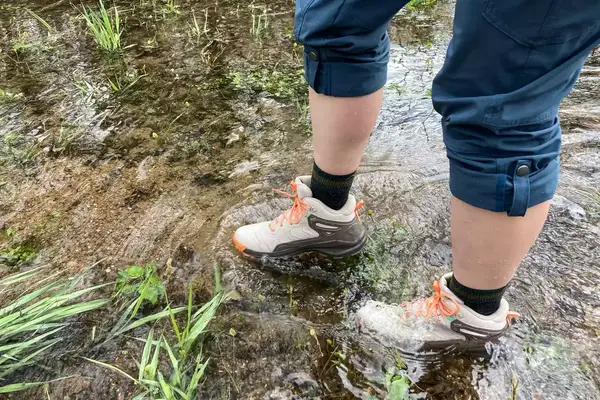 A person wades through water while wearing the Oboz Womenâs Katabatic Mid Waterproof Hiking Boots