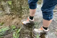 A person wades through water while wearing the Oboz Womenâs Katabatic Mid Waterproof Hiking Boots