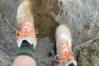 A person walks in shallow water while wearing the Oboz Womenâs Katabatic Mid Waterproof Hiking Boots
