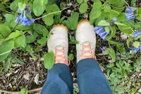 A person walks through plants while wearing the Oboz Womenâs Katabatic Mid Waterproof Hiking Boots