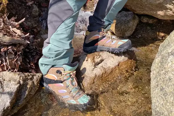 Feet standing on a rock in a river wearing Merrell Men