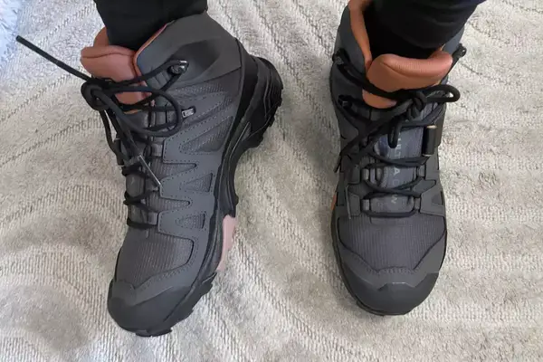 A woman wears Salomon X Ultra 4 Mid Gore-Tex Hiking Boots on top of a white carpet