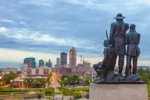 Downtown Des Moines, Iowa with the Pioneers of the Territory statue in the foreground. 