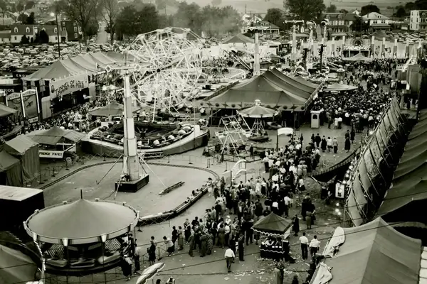 Crowds at a bustling fairground with rides and attractions