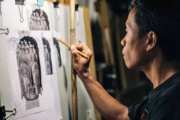 Am artist works with pencil at an easel