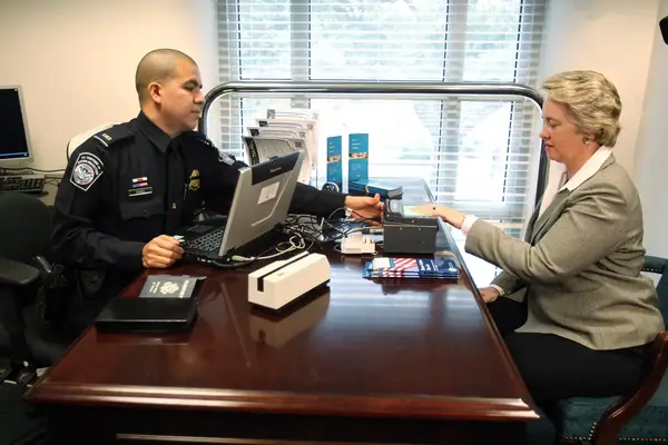 CBP Officer Oscar Perez asks Houston Mayor Annise Parker to place fingers over machine to record a digital scan of finger prints at the new Global Entry satellite center located at City Hall 