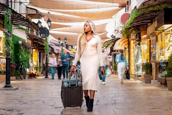 Black woman traveling with suitcase down European street