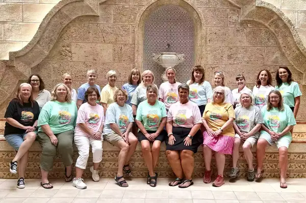 A group of women seated together in front of a patterned wall