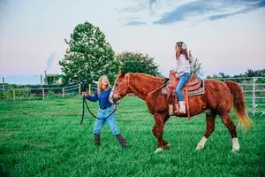 Older woman and young girl on a ranch with horses 