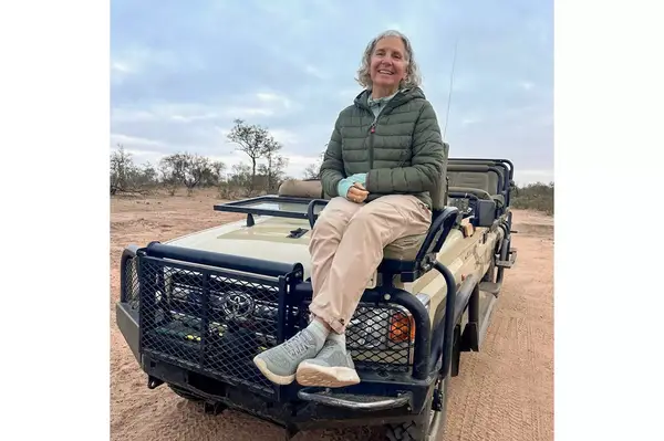 Person sitting on a parked safari vehicle in an outdoor setting