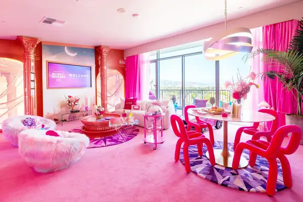A vibrant room with pink decor featuring modern furniture a lounge area and large windows opening to an outdoor view