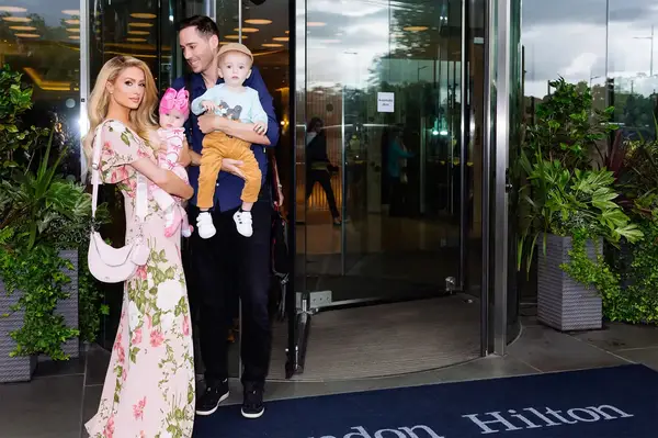 A family with two children standing outside the entrance of a Hilton hotel