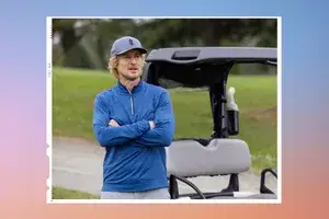 Owen Wilson near a golf cart with crossed arms