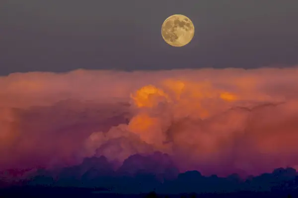 harvest moon rising above storm clouds, western colorado