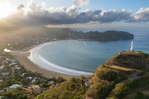 Aerial view of San Juan del Sur with a beach, bay, and a statue on a hill