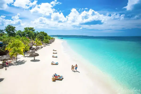 Aerial shot of a family walking down the beach past sun bathers in Negril