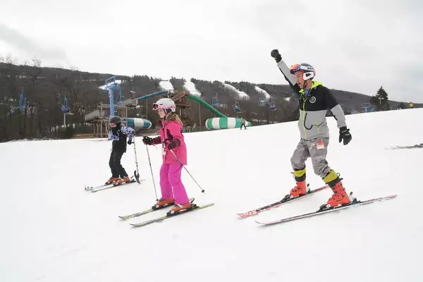 Skier Tyler Carter heads down the slope at Camelback Ski Resort in Tannersville with Ava McEntirer, 12, of West Chester, left, and Madison Hahs, 10, of West Grove, Chester County.