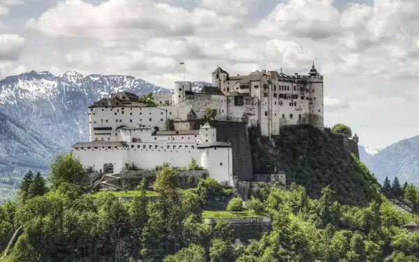 Salzburg, Austria: The Hohensalzburg Fortress in Salzburg Austria with Alps range rising in the distance. Built over several hundred years (from the 11th to 16th centuries), it is one of the largest medieval castles in Europe with a length of 250 m (820 ft)