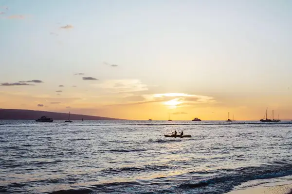 People kayaking at sunset off the coast of Maui, Hawaii