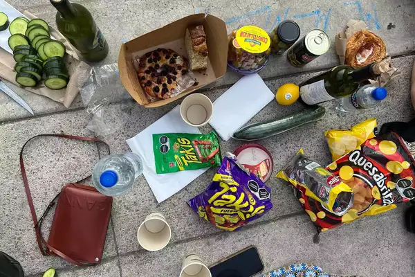 Bottles of wine and little quick snacks being eaten and shared on a sidewalk in Mexico City