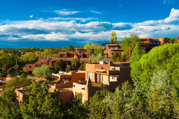 Southwestern-style adobe buildings in a green, scenic Santa Fe landscape