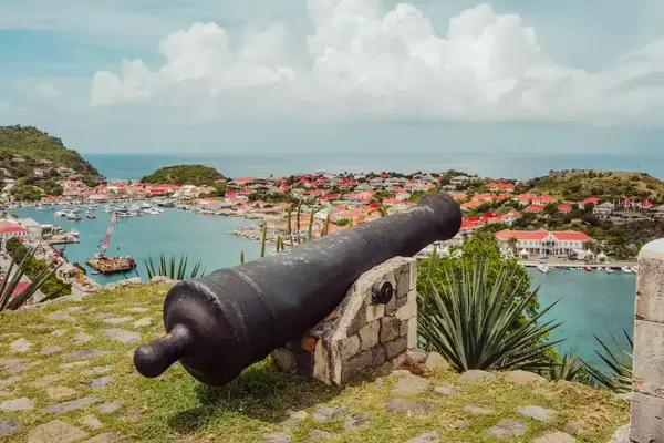 Historic cannon overlooking a coastal town and harbor on a sunny day