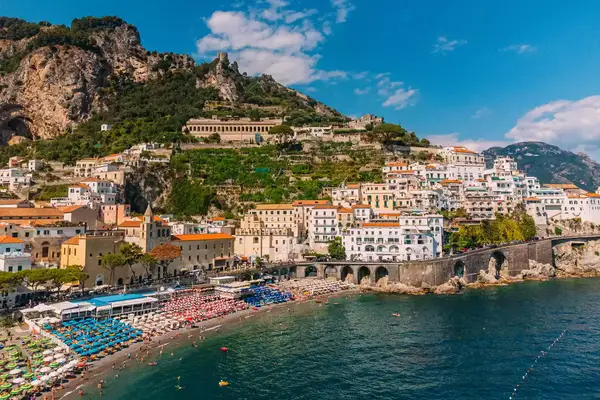 Coastal town with colorful beach umbrellas, hillside homes, and water