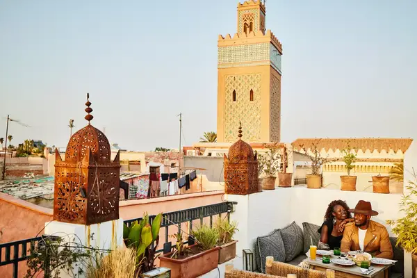 Two people sitting on a terrace enjoying a meal with an ornate building in the background
