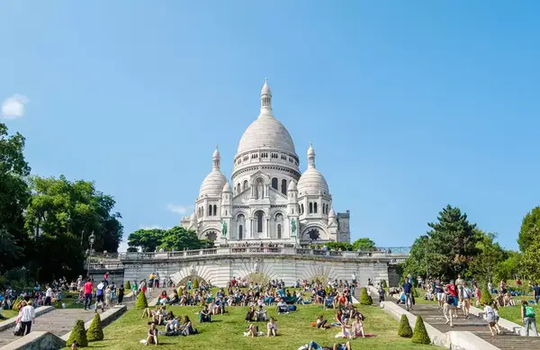 Sacre-Coeur Basilica with tourists gathered on the grassy area in front