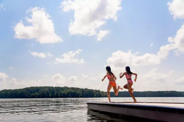 Two girls running to leap off of a dock at a lake in Georgia