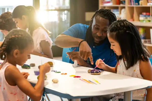A teacher and two children paint rocks at a resort hotel in Georgia