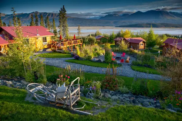 Lodge and cabins with scenic mountain and lake views, surrounded by greenery and pathways in Wrangell-St. Elias National Park