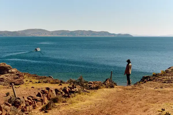 A man standing on a hill looking at a lake.