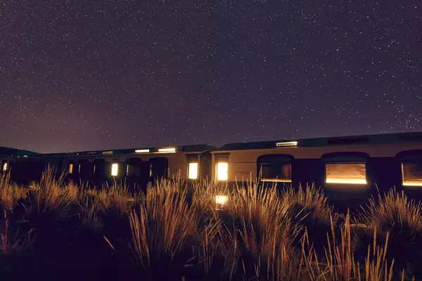 A train at night under a starry sky.