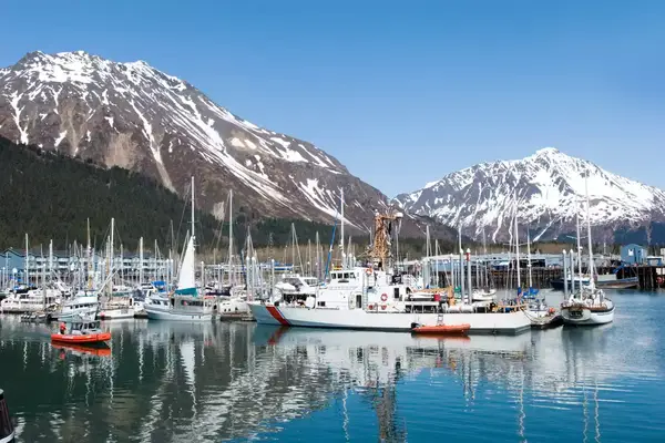 Harbor with boats and docked vessels, snow-capped mountain in the background
