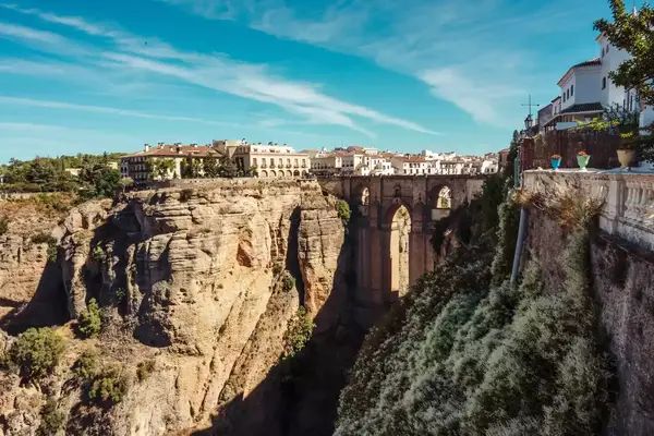 View of the Puente Nuevo bridge in Ronda, Spain, spanning a deep gorge with buildings and natural scenery around