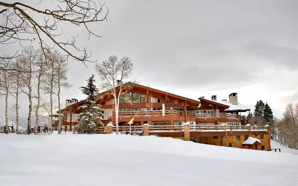 An exterior shot shows the wood-accented exterior of Stein Eriksen Lodge on a snowy winter day
