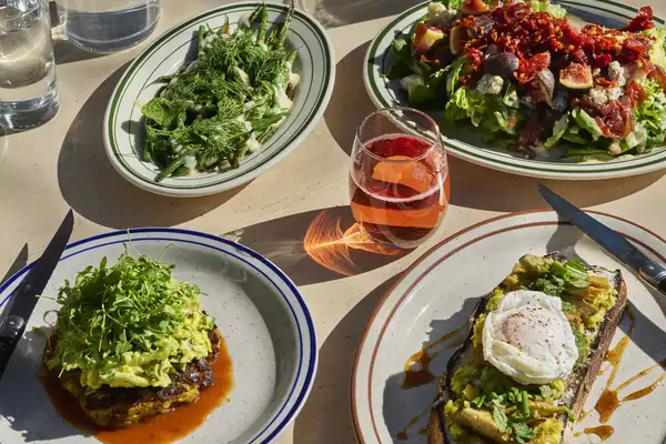 Four plates of food with a glass of rose at a restaurant in California