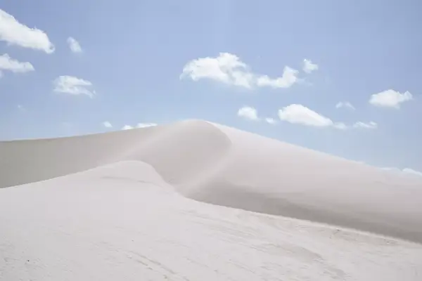 White sand dunes and a blue sky with fluffy clouds