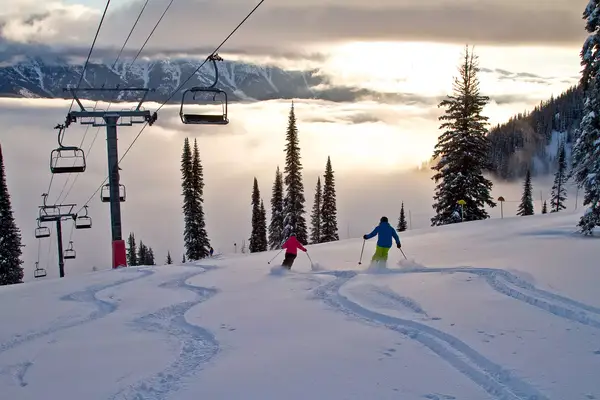 Skiers going down a slope at sunrise