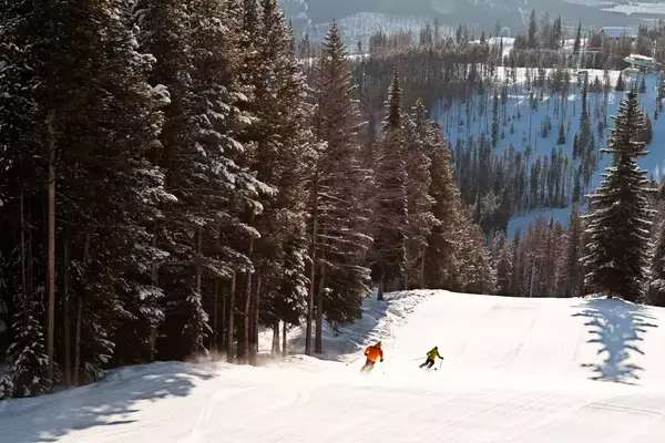 Two skiers going over slopes