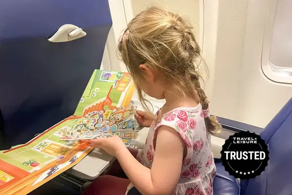 A child reading an illustrated book while seated on an airplane