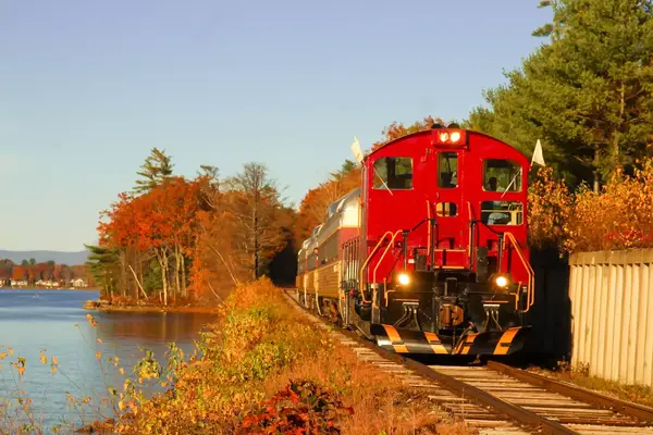 A red train engine along a lakeside track